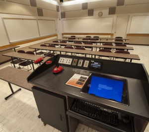 Classroom 426, lectern with computer, rows of rectangle tables with chairs. 